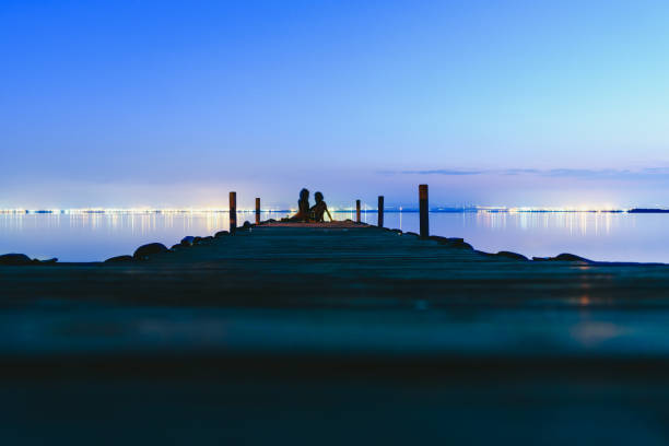 istock People resting relaxed on a pier on a lake at sunset with calm water 1705654577