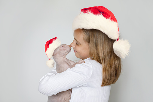 Christmas portrait of happy cheerful lovely child girl Santa with cat Santa on white background
