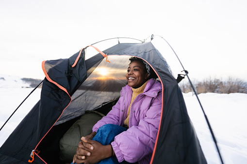 Photo of a smiling African American woman camping alone in a tent
