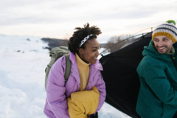 istock Adventurous couple setting up a camping tent on a snowy mountain 1705686749