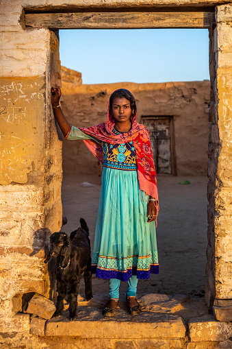 Indian young girl sitting next to her house in desert village, Rajasthan, India.