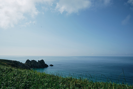 Scenic views from the cliffs above Pedn Vounder Beach, Cornwall over the beautiful calm June morning sea in the southwest of England.