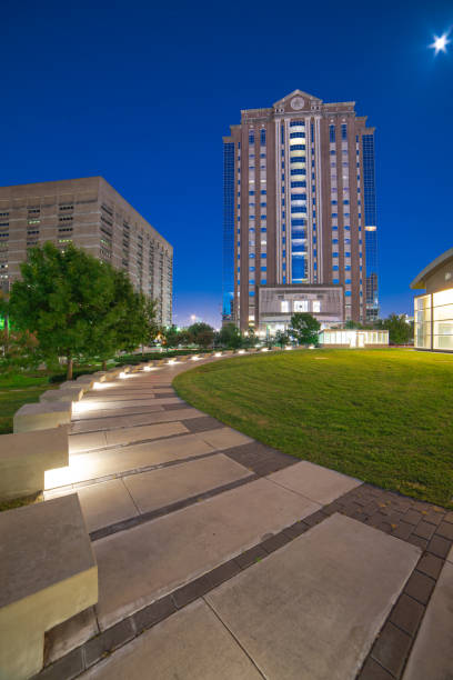 istock Houston municipal courts with Illuminated pathway concrete sidewalk at park square, downtown skyscrapers, office buildings during evening blue hour 1705704528