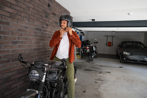 Man putting on a helmet before riding his bike in garage.