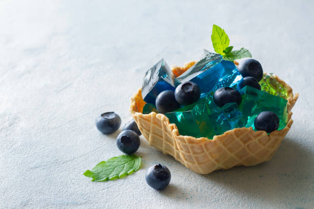 gelée de fruits aux myrtilles fraîches décorées de feuilles de menthe, servie dans un bol à gaufres, concept de dessert d’été - gelatin dessert blueberry blue dessert photos et images de collection