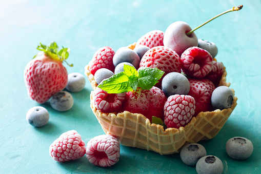 Frozen summer fruits with mint leaf served in waffle bowl concept