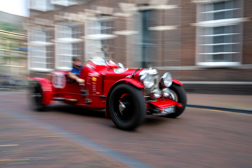 Bentley Special old N0 1 MKVI 1947 vintage race car in bright red driving on the street in Zwolle. Panning photo with heavy motion blur.