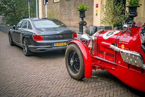 Bentley Flying Spur luxury sedan and vintage Bentley Special old No 1 race car parked on the street in front of three star Michelin restaurant Librije in Zwolle, Overijssel, Netherlands.