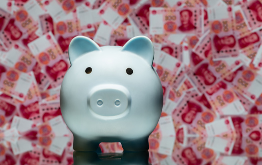 Piggy bank against the background of many 100 Chinese yuan bills