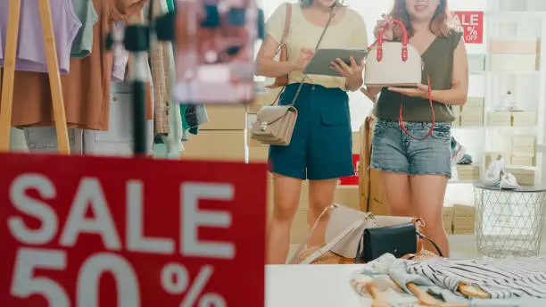 Photo of Closeup of young Asian women live streaming on phone show new collection fashion clothes to customer at shop. SME small business e-commerce.