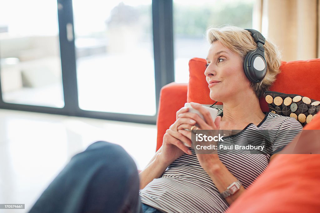 Mulher tomando café e escutando fones de ouvido - Foto de stock de Fone de Ouvido - Equipamento de som royalty-free