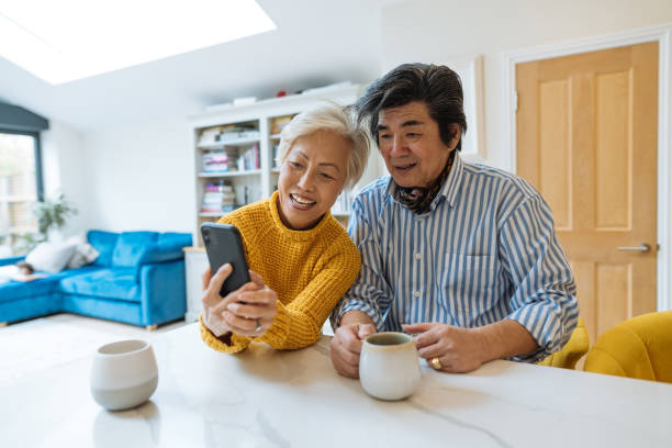 istock Asian senior couple at home, using smart phone and drinking coffee 1705754885