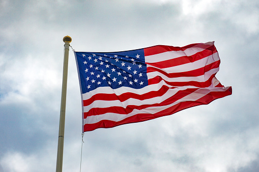 American Flag waving in the wind, with beautiful red white and blue colors.