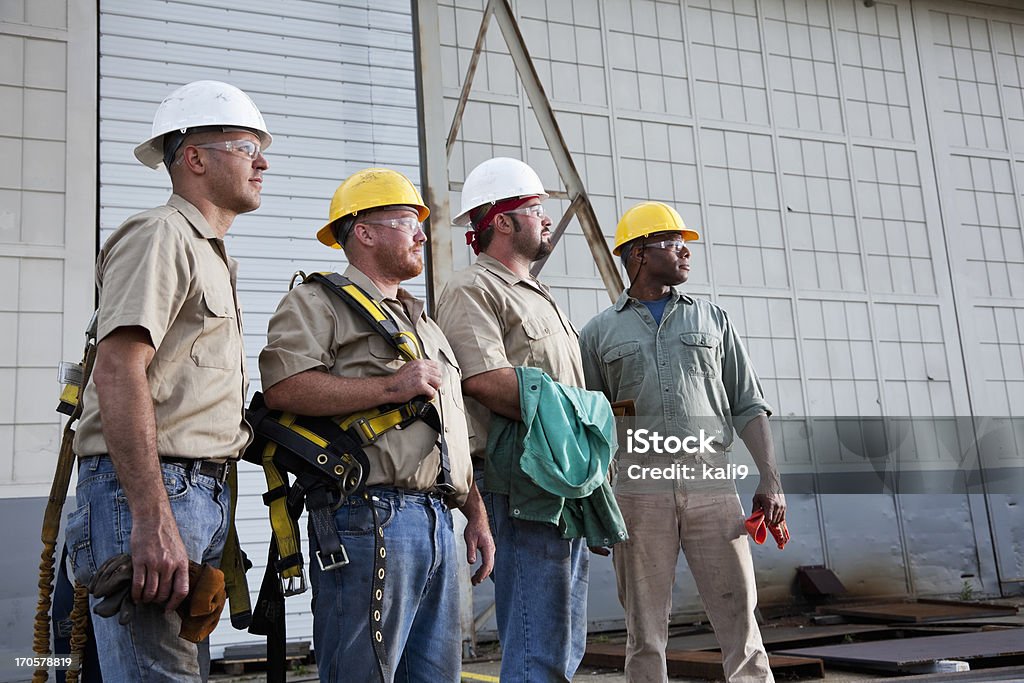 Team of construction workers with harnesses Multi-ethnic construction workers (20s and 30s) with hard hats, safety glasses and harnesses. Group Of People Stock Photo