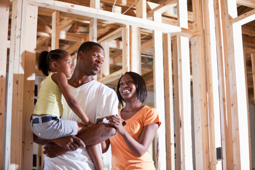 African American family standing in house under construction.