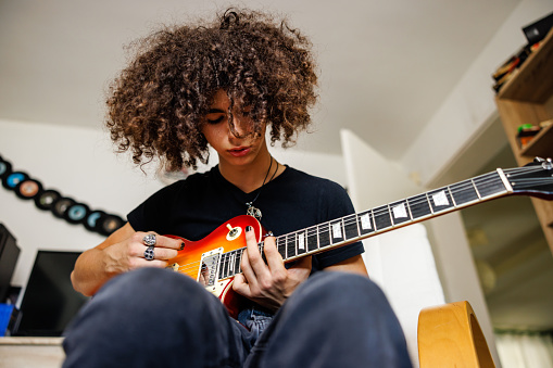 Boy with curly hair play electric guitar