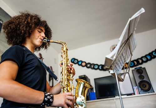 Young musician with curly hair enjoys saxophone play