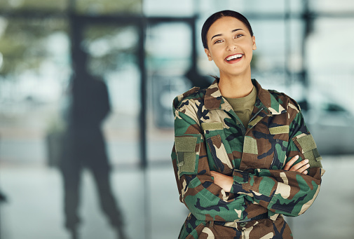 Portrait of woman soldier with smile, confidence or pride, outside army mockup with arms crossed. Professional military career, security and courage, girl in camouflage uniform at government agency.