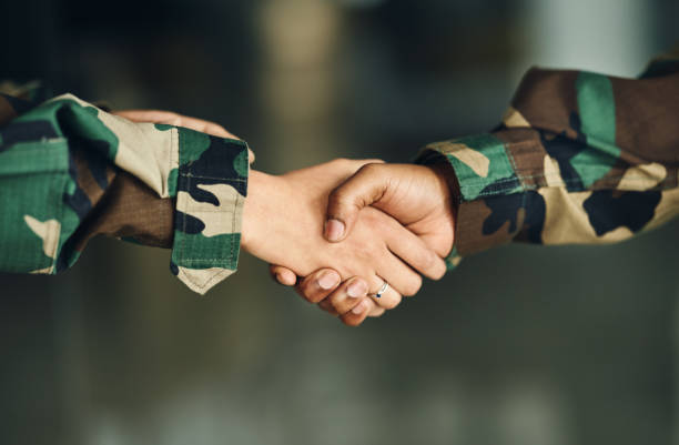 istock Meeting, army or shaking hands for partnership, teamwork or deal in war, agreement or unity together. Closeup, soldiers or handshake for team fight, thank you or gratitude in solidarity or military 1705803703