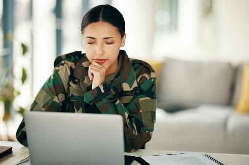 Laptop, serious soldier and woman in home, planning and problem solving. Computer, veteran on internet and technology online to search, thinking of army idea and reading military email in living room