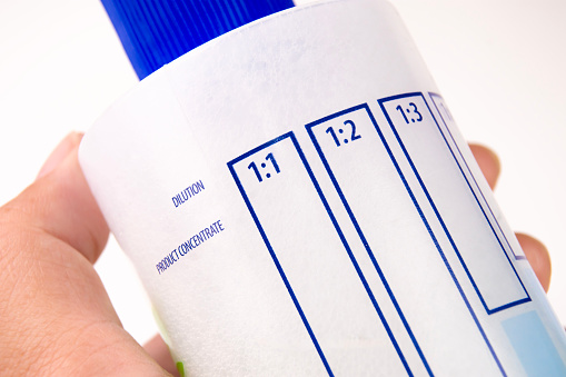 Close up a dilution ratio label of concentrated liquid chemicals on plastic bottles, human hand holding a plastic bottles for liquid chemicals.