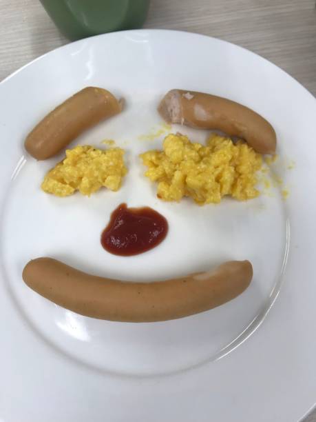 istock Sausage with omelette egg and ketchup sauce on white plate in face style 1705824001