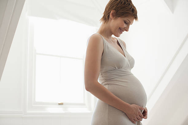 mulher grávida segurando a barriga - dress human pregnancy young women women imagens e fotografias de stock