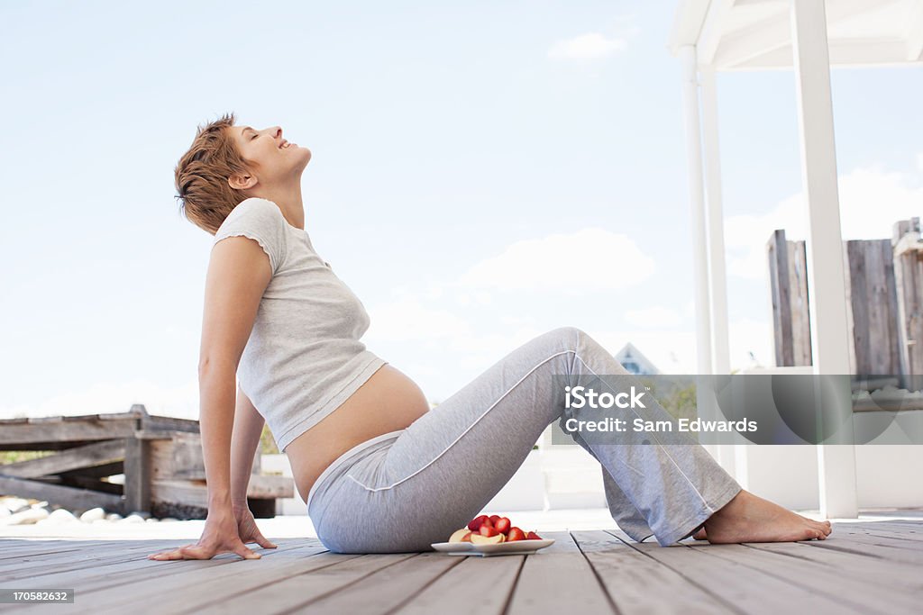 Kobieta w ciąży jedzenie owoców na pokładzie - Zbiór zdjęć royalty-free (20-24 lata)