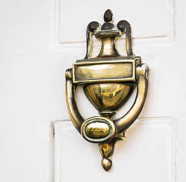 An antique brass door knocker on a painted wooden door.