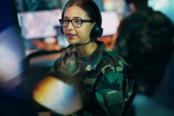istock Army command center, computer and woman in headset, global surveillance and tech for communication. Security, intelligence and soldier at desk in military office at government cyber data control room 1705839230