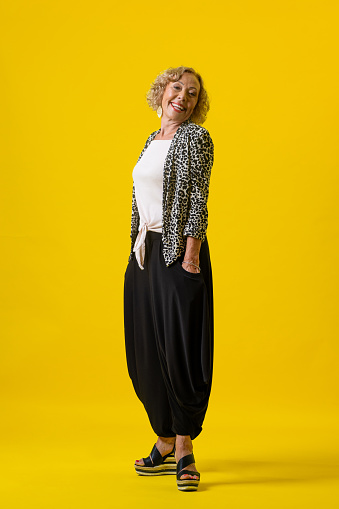 Full studio portrait of a senior female posing in smart casual clothing. She is smiling looking into the camera.