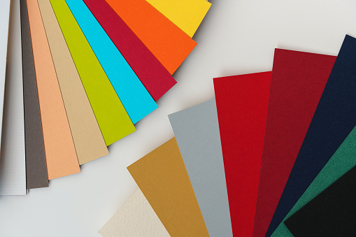 Colourful paper swatches on white desk, closeup detail