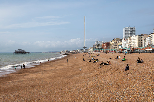 Brighton, United Kingdom - Sep 26, 2023:  Seafront and beach at Brighton in East Sussex, England. Viewed from the pier with British Airways i360 observation tower.