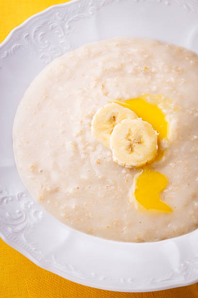 Porridge with banana slises and melted butter in white plate above yellow napkin