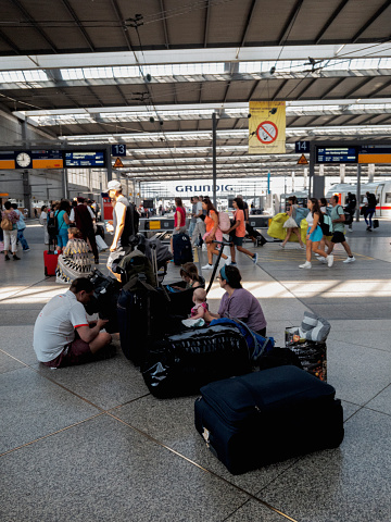 Munich, Germany - August 15, 2023: A family waits for the train at a train station in Munich.
