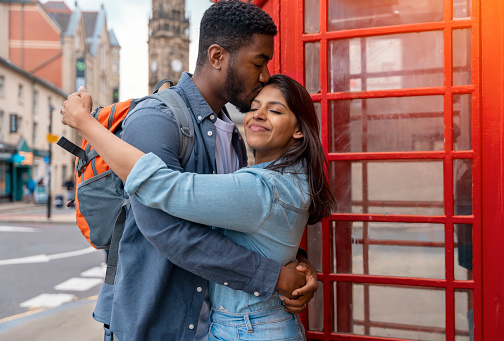 two friend, couple using a camera,   taking selfie against a red phonebox, watching photos on camera, having a fun  in the city of England.Travel Lifestyle concept
