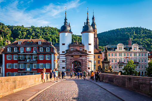 Heidelberg, Germany - August 25, 2023:  Pedestrians on the old stone bridge with gate to famous city Heidelberg in Germany