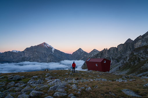 A man enjoying the morning view from a bivacco in the Italian Alps.