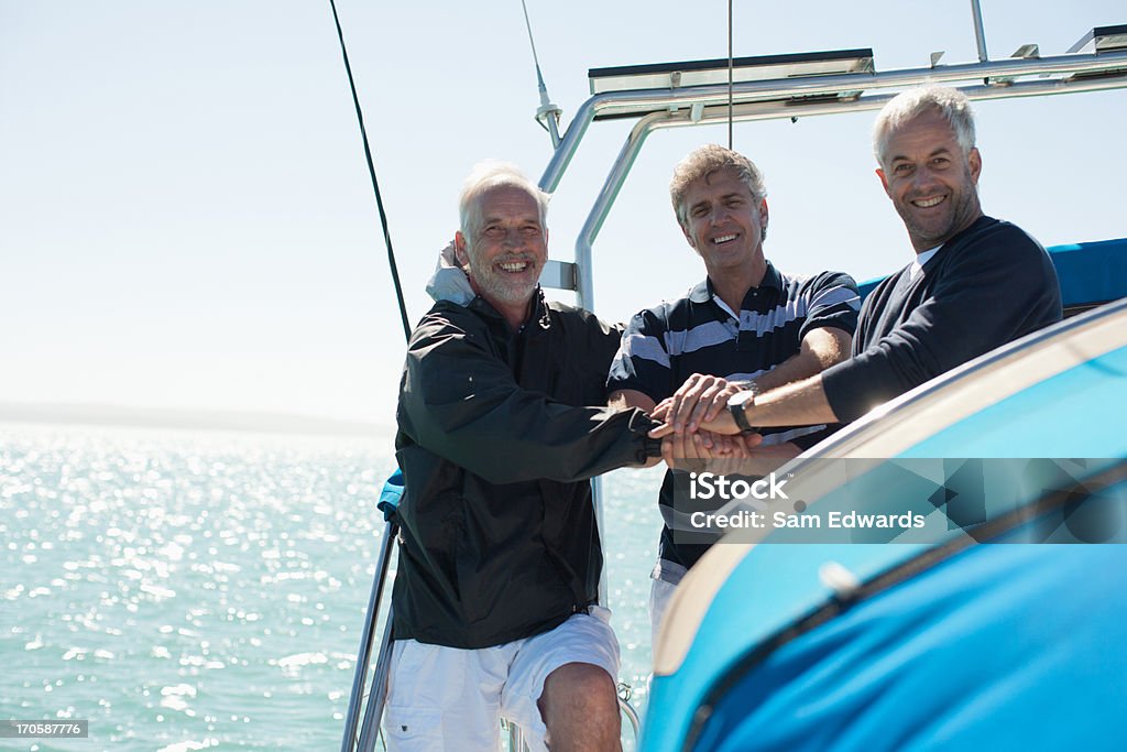 Amici clasping mani sul ponte della barca - Foto stock royalty-free di Andare in barca a vela