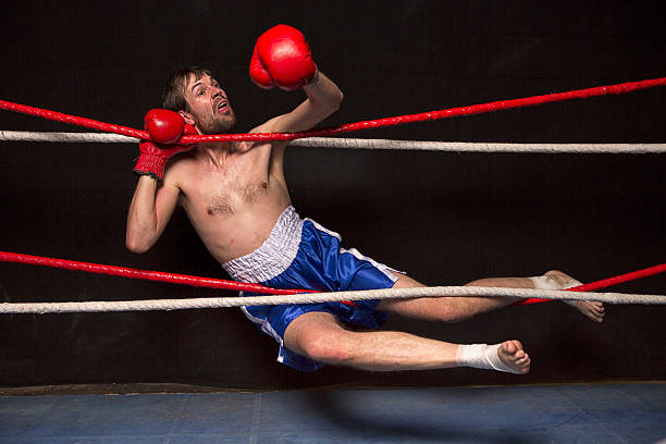 молодой человек запутавшись в бокс кольцо веревки - boxing ring фотографии стоковые фото и изображения