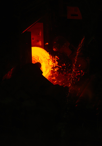 Hot steel slab passes along a rolling machine at a steel plant.