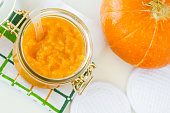 Homemade pumpkin face mask in a glass jar. Natural autumn beauty treatment and spa recipe. Top view, copy space.