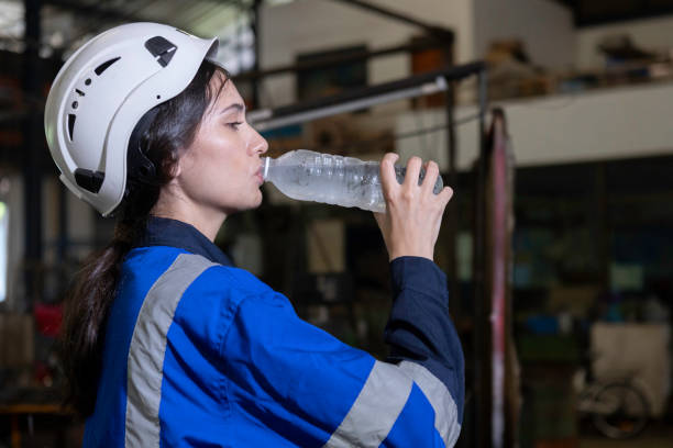 istock Women engineer drinking water from plastic bottle after working at factory during break. Drinking pure water refreshes body. Image female drinking water for advertise. 1705891909