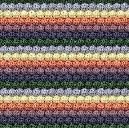 Geometric volumetric seamless knitted pattern in the form of bumps. The texture is crocheted from multi-colored yarn. Autumn color combination.