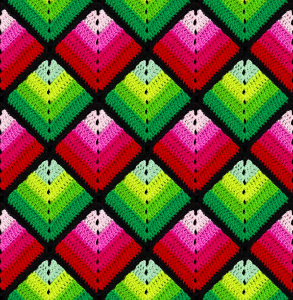 Seamless knitted pattern in the form of gradient rhombuses is crocheted with multi-colored threads. Patchwork style. Acrylic blanket.