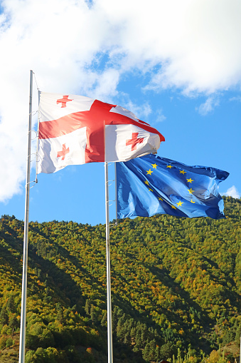Georgian flag and EU Flag Waving on Sunny Blue Sky