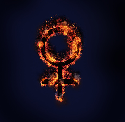 Universal symbol for female, burning on a blue-black background with copy space. The symbol also represents the planet Venus.