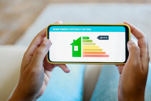 istock Home energy performance: Hands hold mobile phone looking at house efficiency rating app - Environment and electricity concept 1705917300
