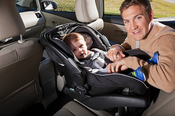 Father with baby in car seat Young father (20s) with baby boy (8 months) strapped in a car seat. Sc0601 stock pictures, royalty-free photos & images