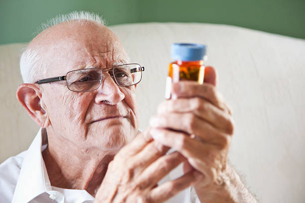 uomo anziano leggendo bottiglie di medicina - sc0570 foto e immagini stock